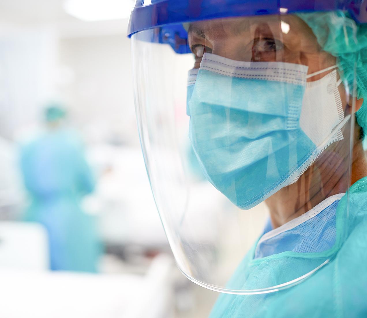 Närbild på en läkare som bär andningsskydd och visir